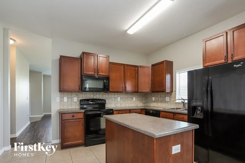 A kitchen with wooden cabinets and a black refrigerator.