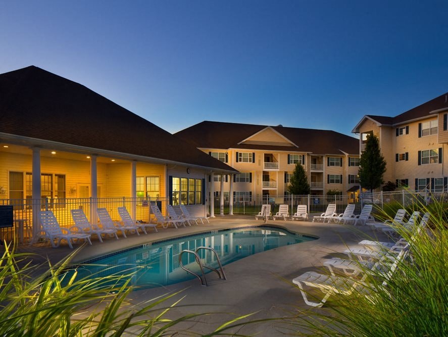 A pool surrounded by lounge chairs in front of a building.