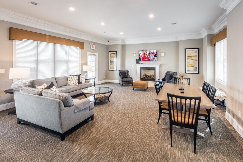 A living room with a grey couch, a wooden table and a fireplace.