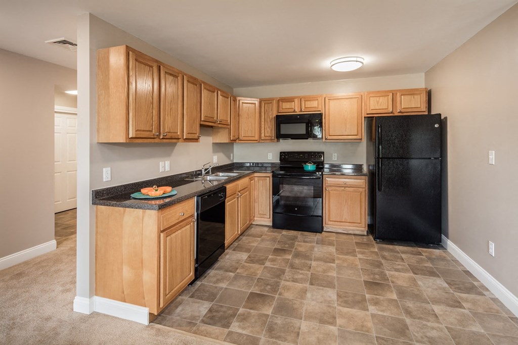 A kitchen with black appliances and wooden cabinets.