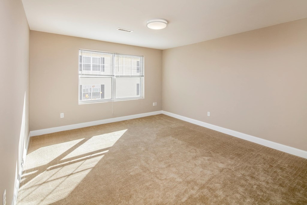 A room with a carpeted floor and a window.