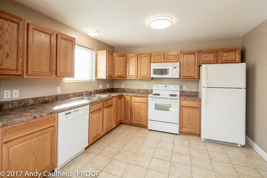 A kitchen with wooden cabinets and white appliances.