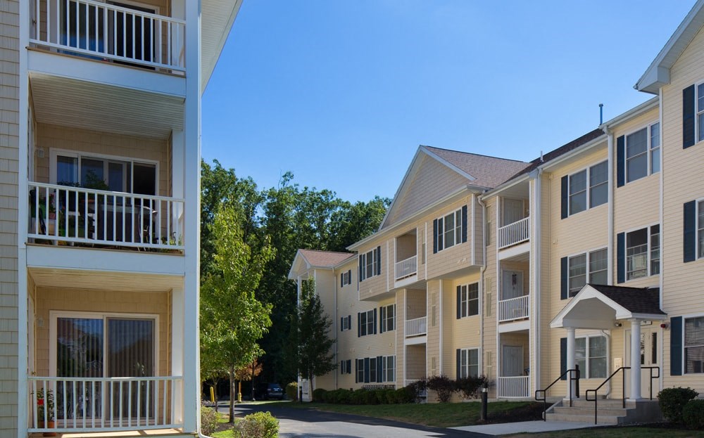 A row of apartment buildings with balconies and trees in the background.