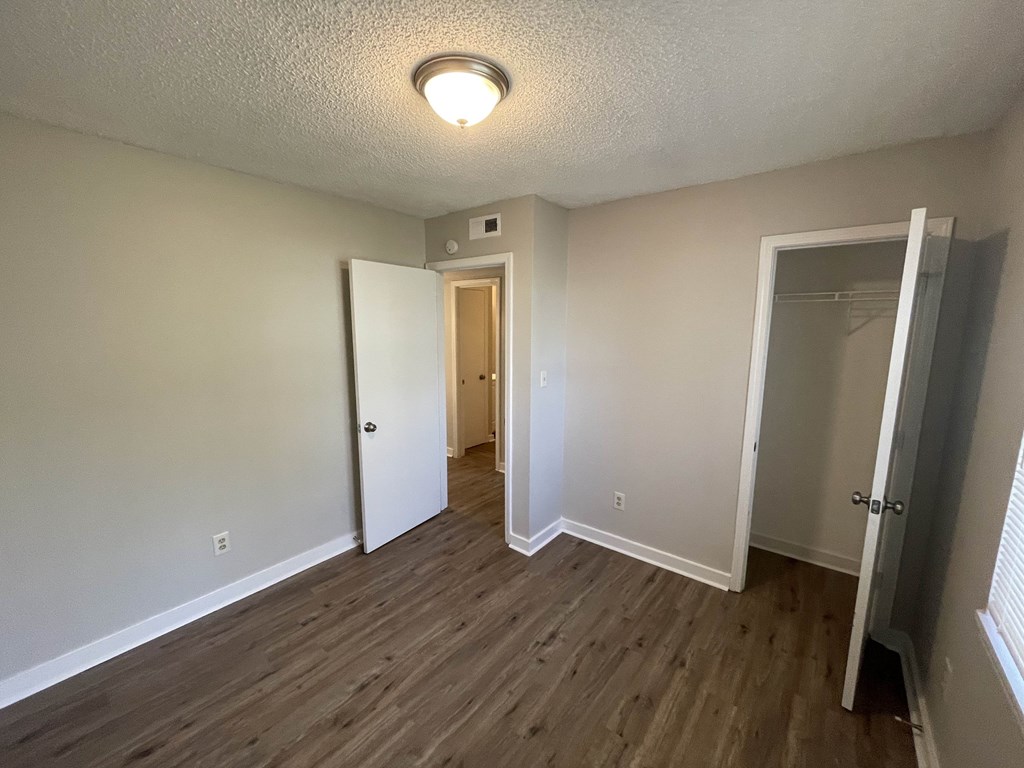 an empty living room with wood flooring and a closet