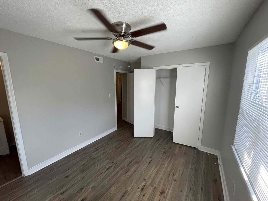 an empty living room with a ceiling fan and a closet
