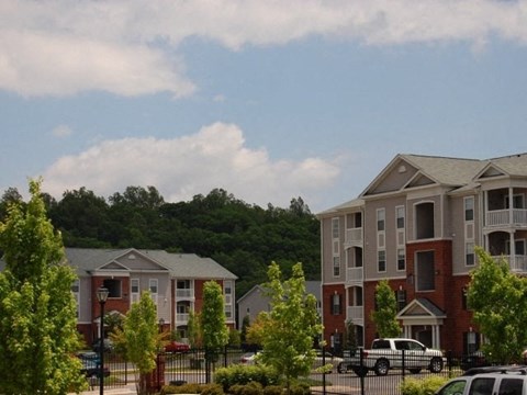 A row of apartment buildings with trees in front.