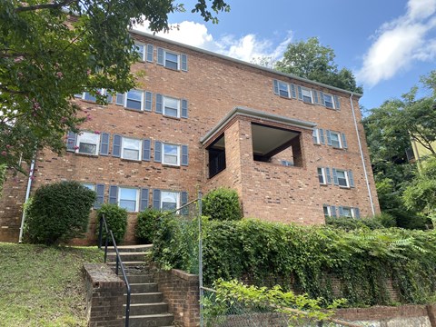 A red brick building with a staircase leading to a doorway.
