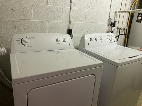 Two white front loading washing machines in a laundry room.