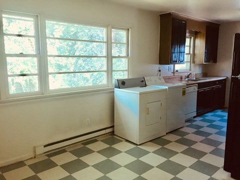 A kitchen with a checkered floor and white appliances.