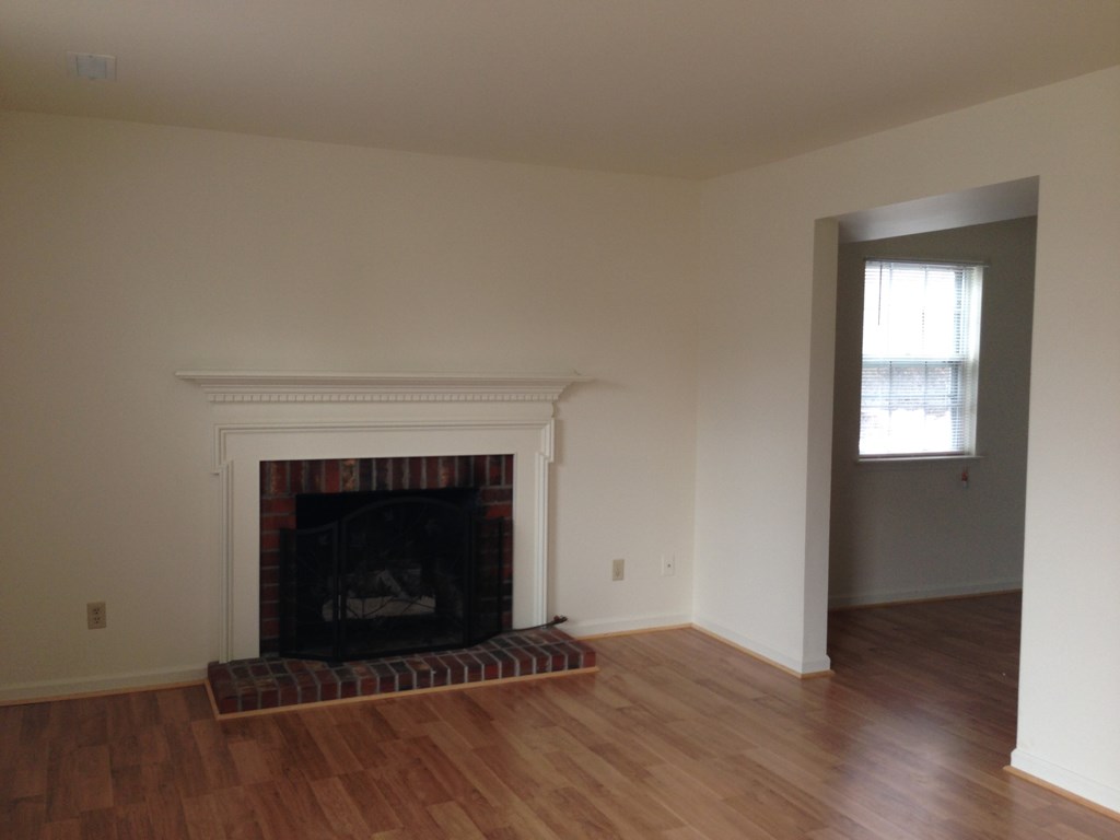 an empty living room with a fireplace and wooden floors