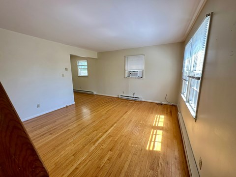 A room with wooden flooring and a window on the right side.