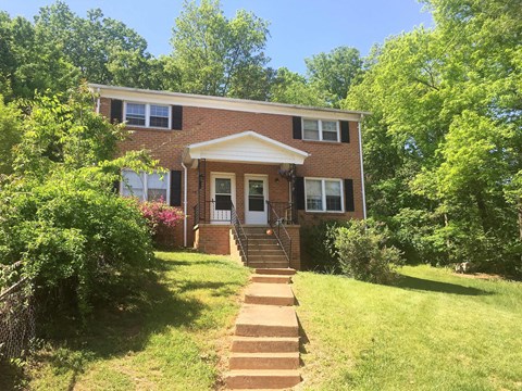 the front of a brick house with a lawn and stairs