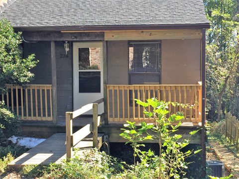 A small house with a white door and a wooden porch.
