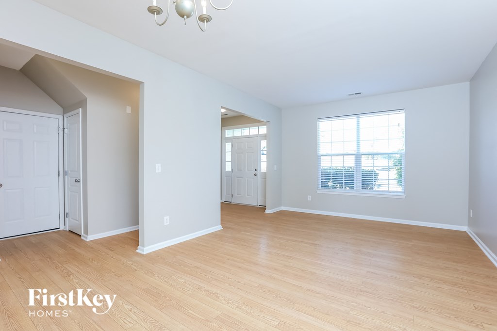 a living room with wood flooring and white walls and a window