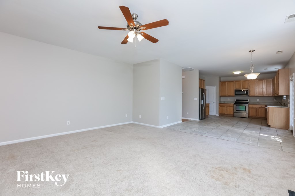 an empty living room and kitchen with a ceiling fan