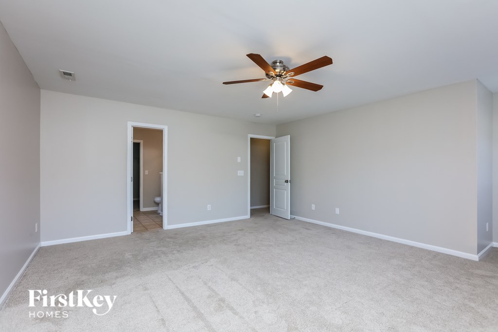 a spacious living room with ceiling fan and white carpet