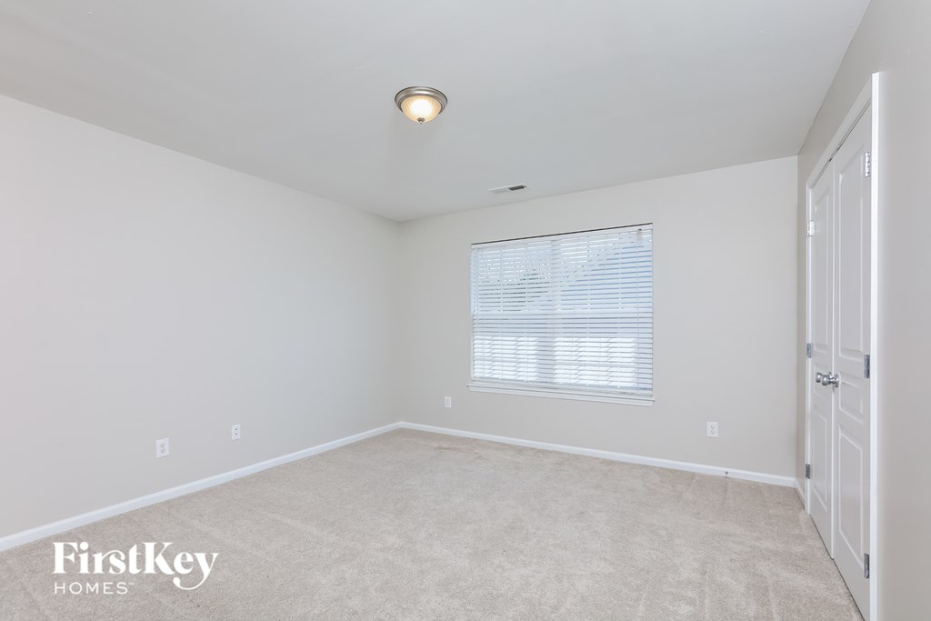 a bedroom with white walls and white carpet and a window