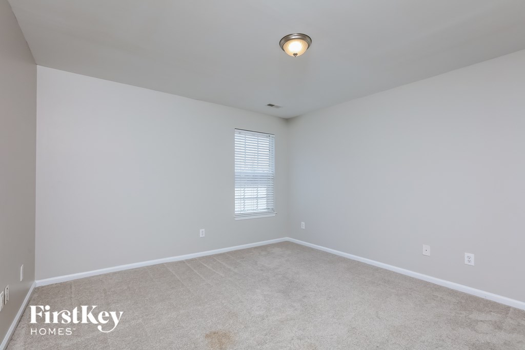 a bedroom with white walls and carpet and a window