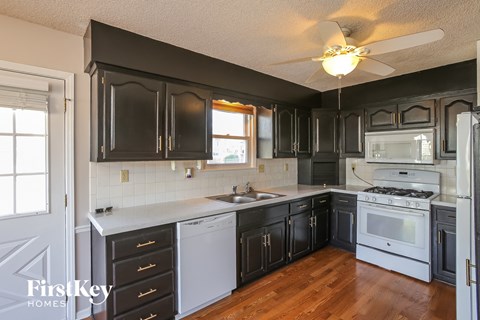 A kitchen with black cabinets and a white stove top oven.