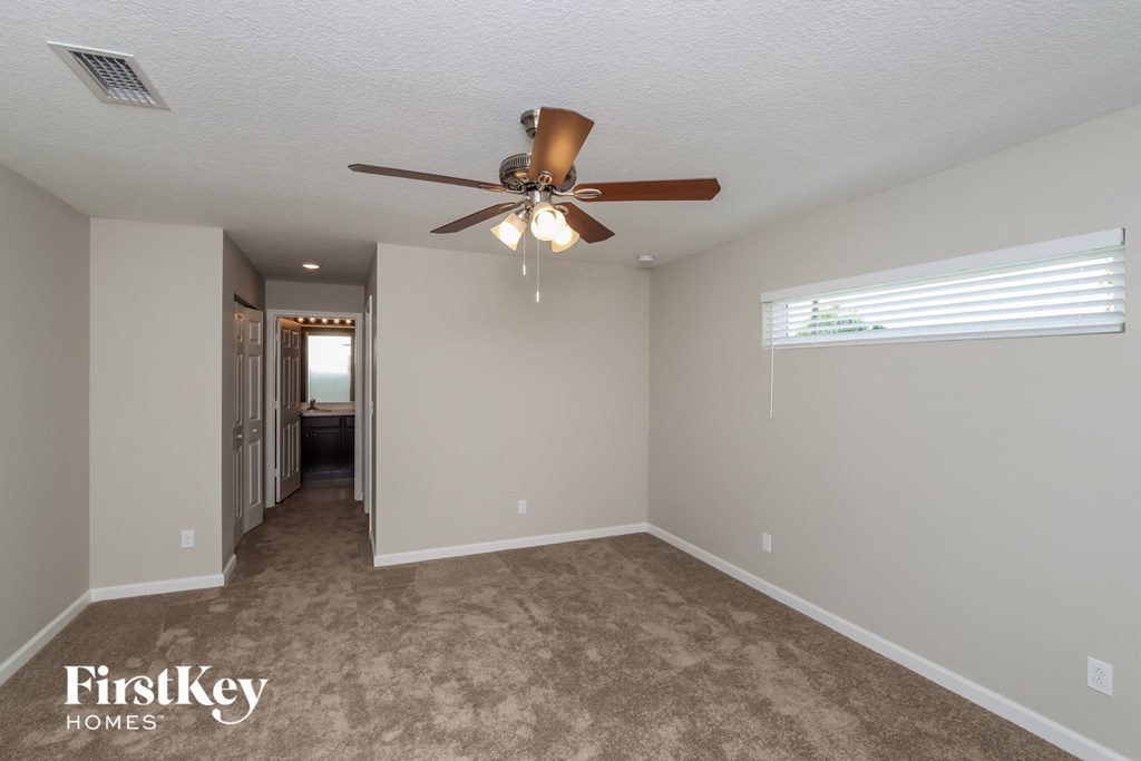 A spacious room with a carpeted floor and a ceiling fan.