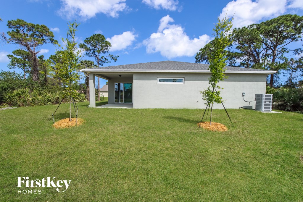 A house with a grassy lawn and trees in the background.