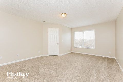 a spacious living room with carpet and a white door