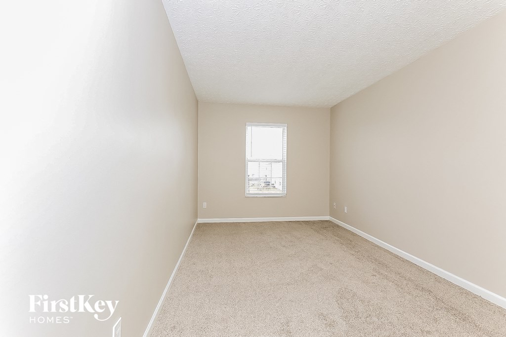 a spacious bedroom with white carpet and a window