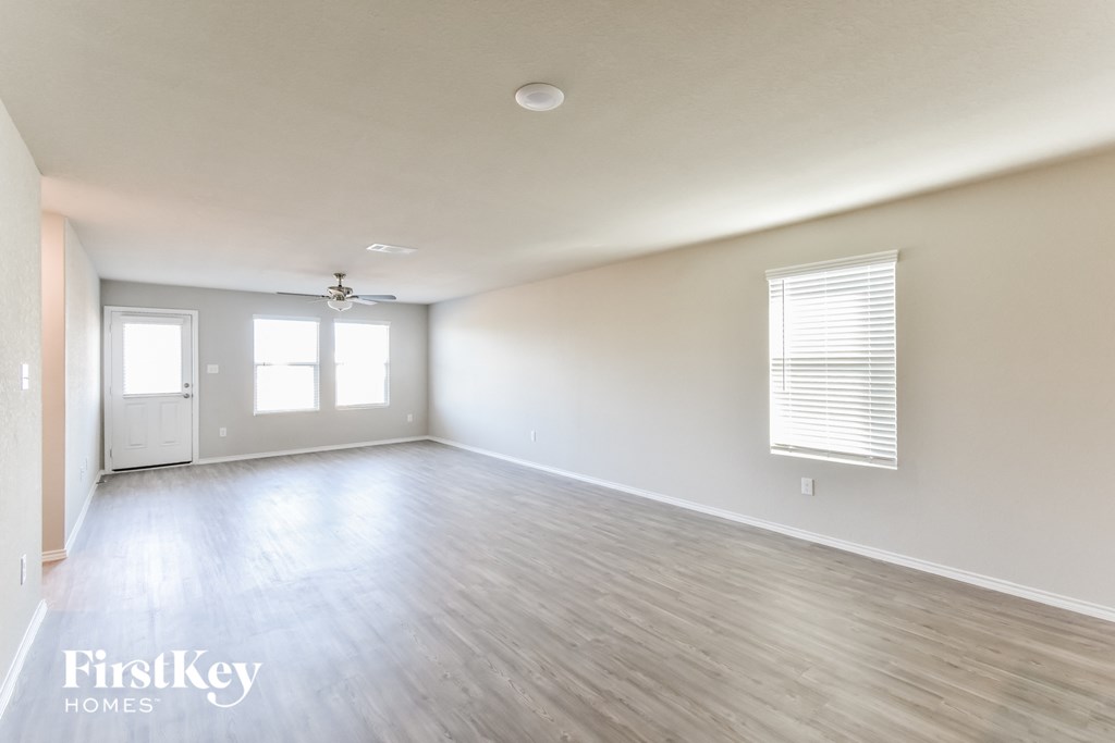 A spacious room with wooden flooring and a window with blinds.
