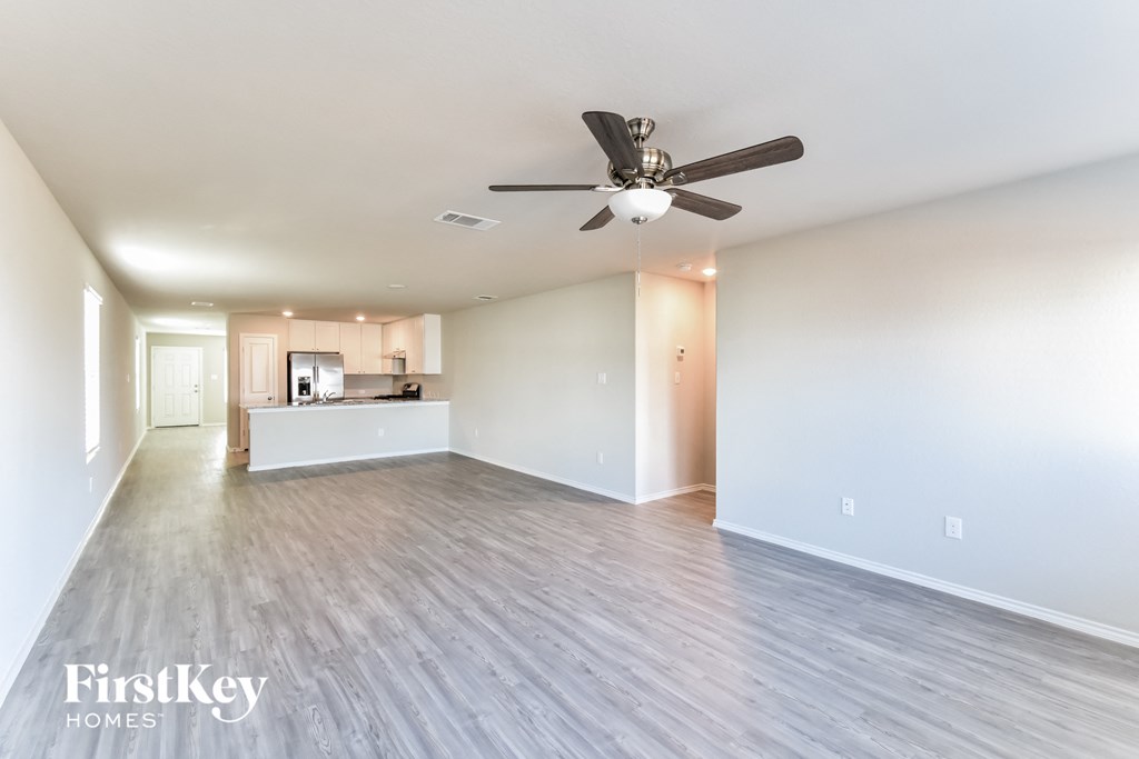 A spacious room with a ceiling fan and lighting fixtures.