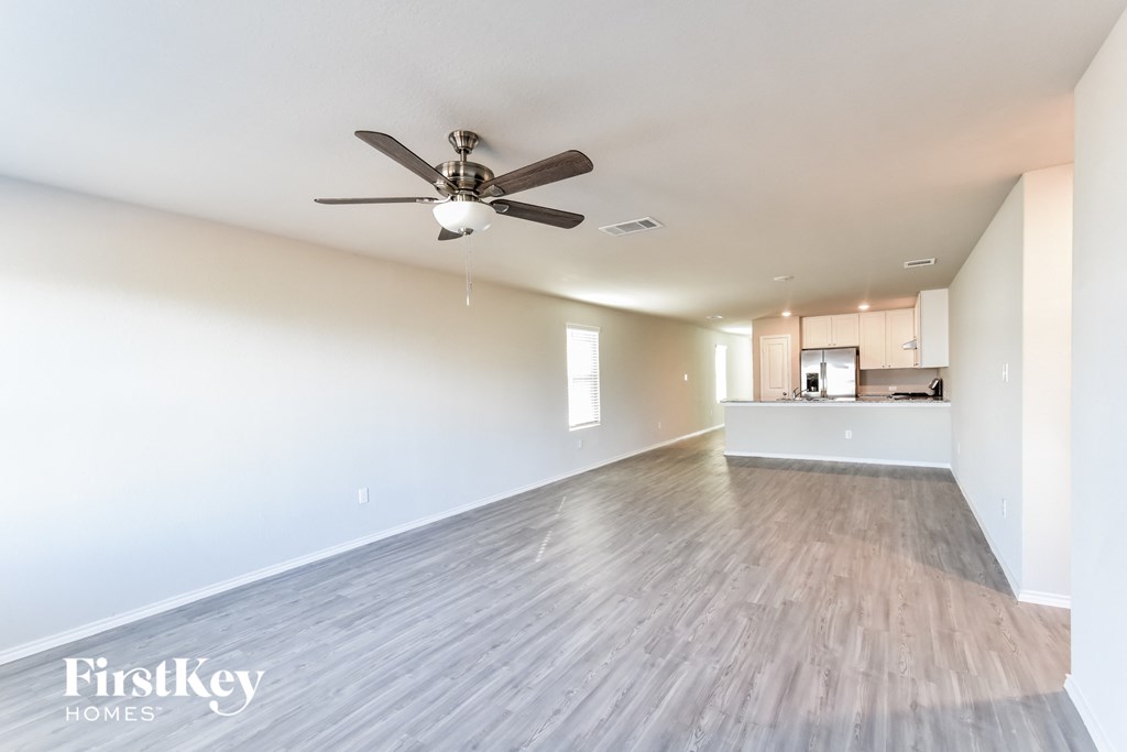 A spacious room with a ceiling fan and wooden flooring.
