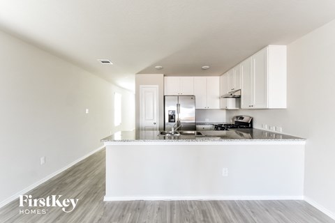 A modern kitchen with white cabinets and a wooden floor.