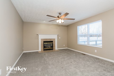 A spacious room with a fireplace and a ceiling fan.