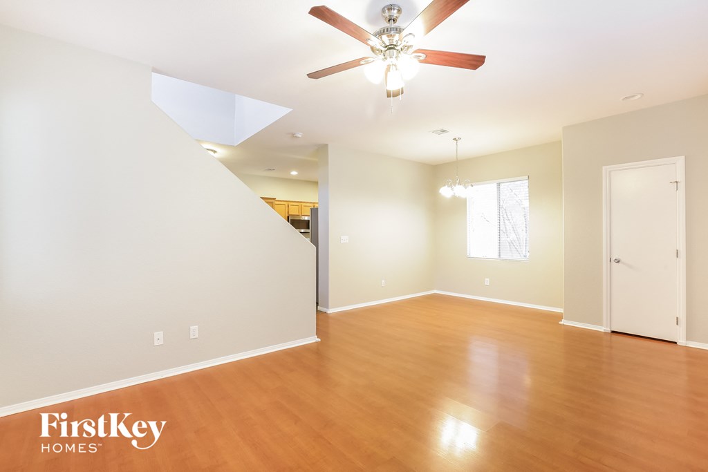 an empty living room with wood floors and a ceiling fan