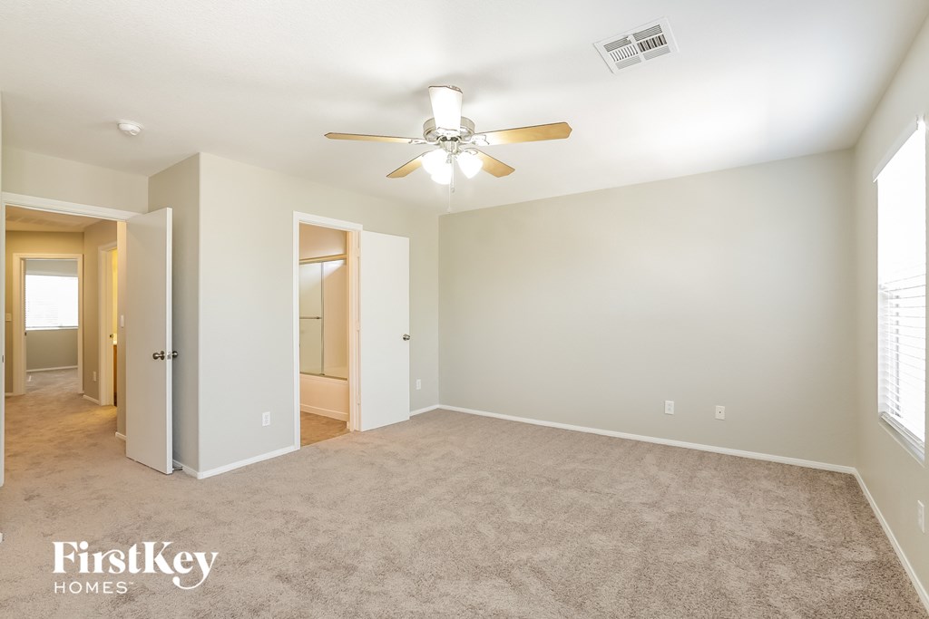 a empty living room with a ceiling fan and a door to a closet