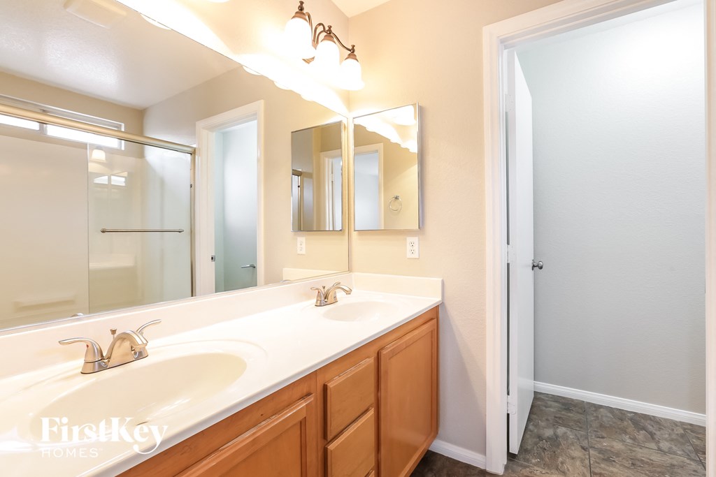the master bathroom has a large vanity with two sinks and a large mirror