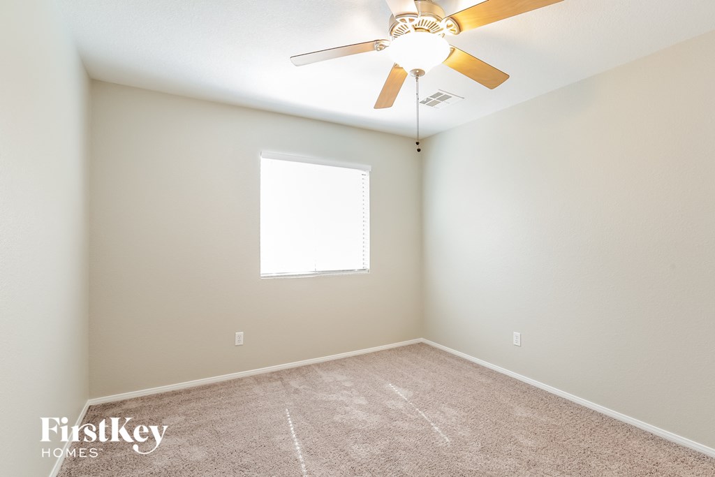 a empty room with a ceiling fan and a window