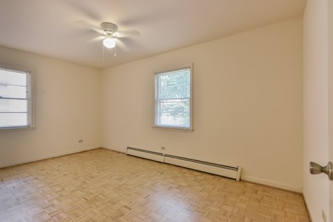 A room with a ceiling fan and a window with a view of trees.