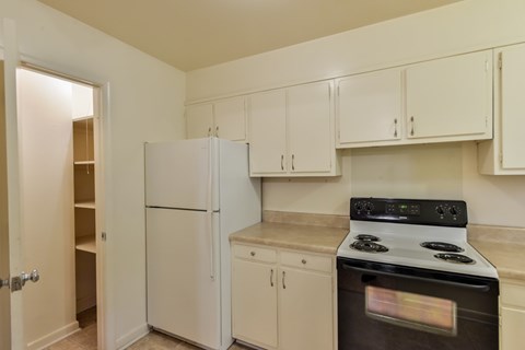A kitchen with a white fridge, stove and cabinets.