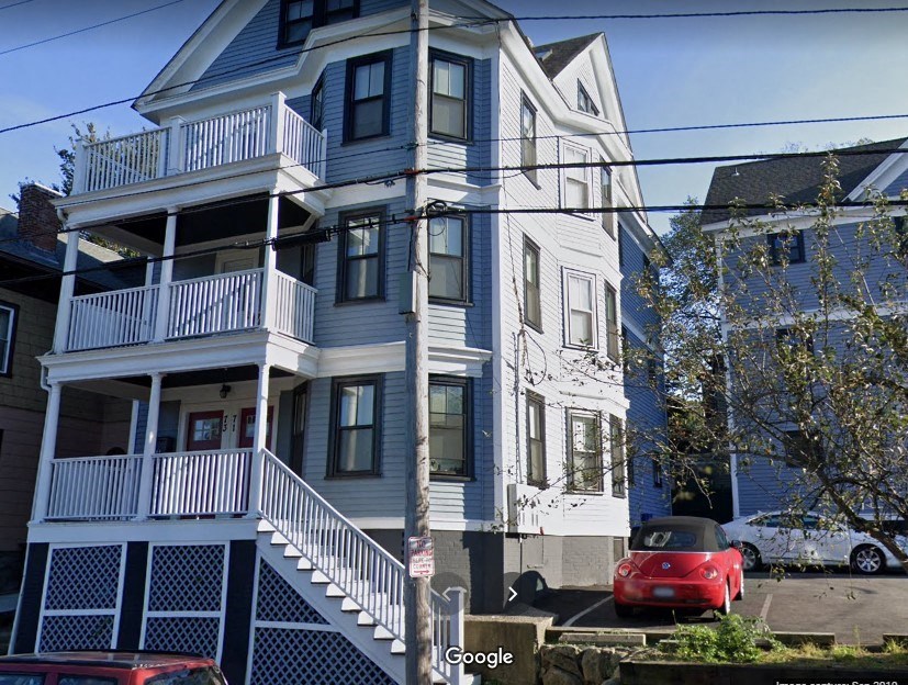a blue and white house with a red car parked in front of it