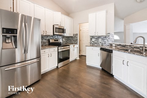 a large kitchen with stainless steel appliances and white cabinets