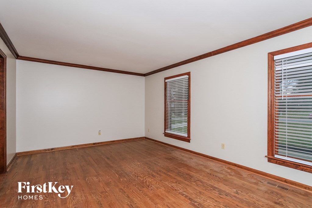 A room with wooden floors and a window with blinds.
