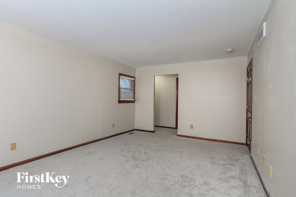 A spacious empty room with a window and a door.