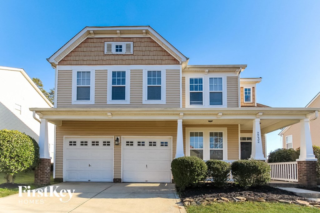 a tan house with white garage doors