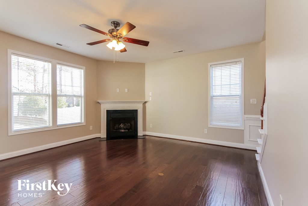 an empty living room with a ceiling fan and a fireplace