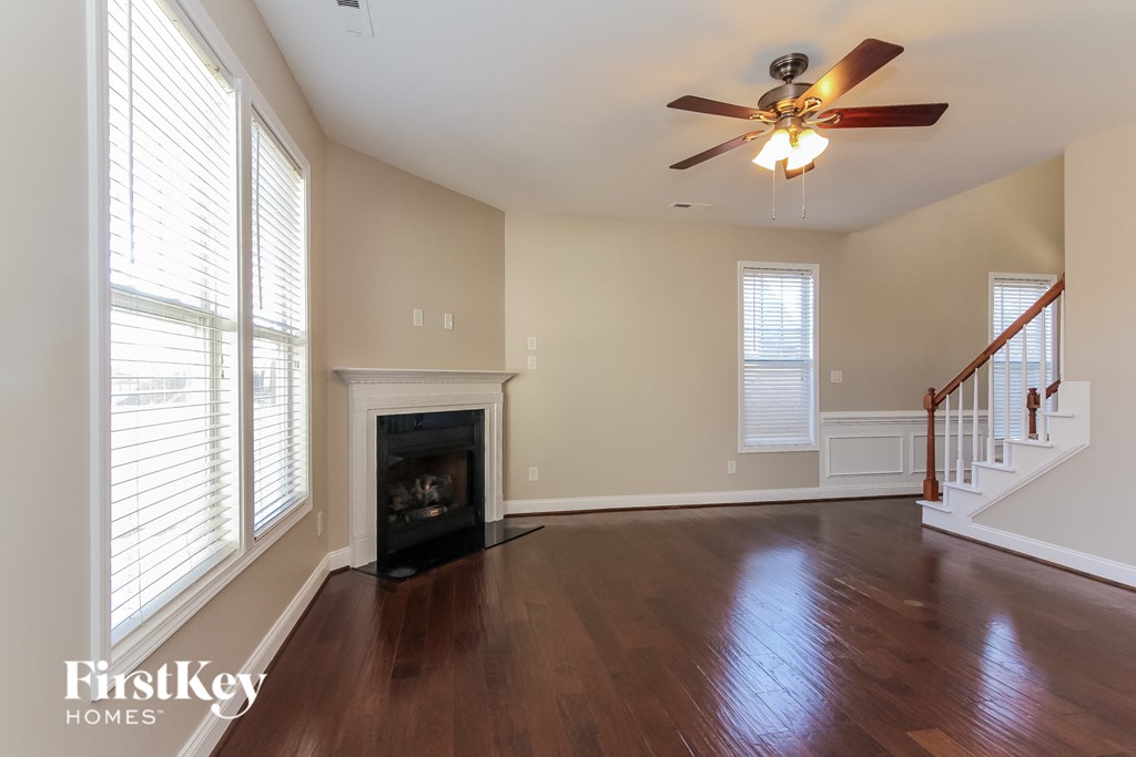an empty living room with a fireplace and a ceiling fan