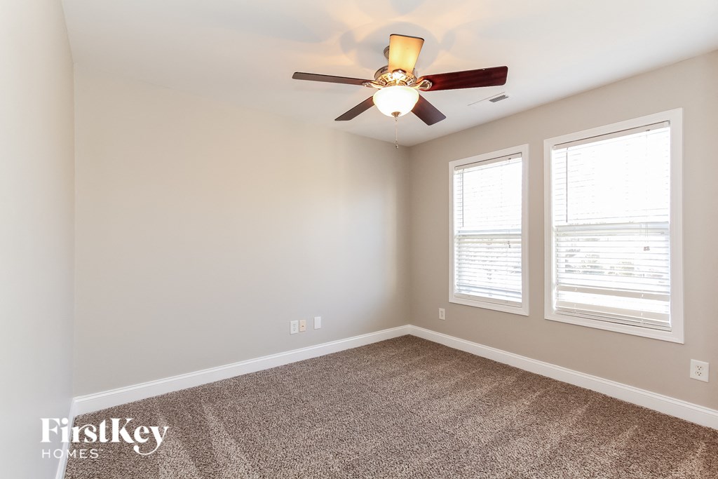 a bedroom with a ceiling fan and two windows
