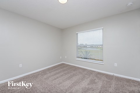 the living room of an apartment with carpet and a window