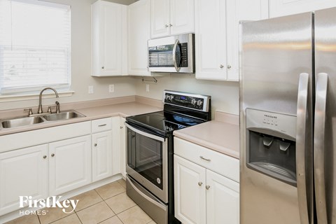 A kitchen with a stainless steel refrigerator, oven, and sink.