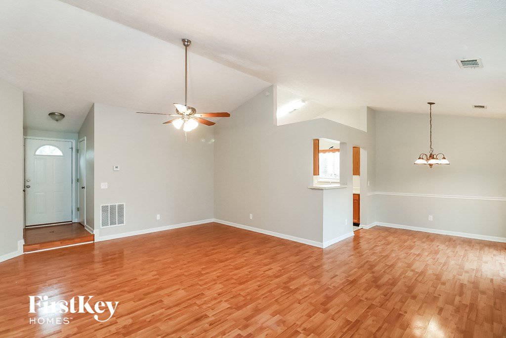 A spacious room with wooden floors and a ceiling fan.