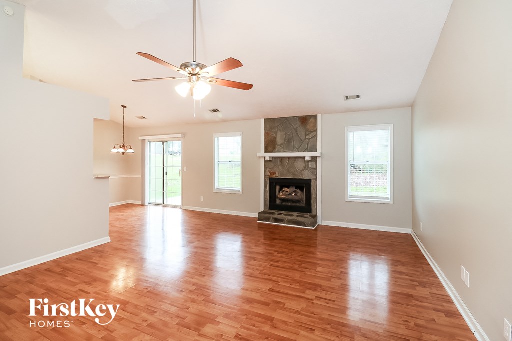 A spacious living room with a fireplace and a ceiling fan.